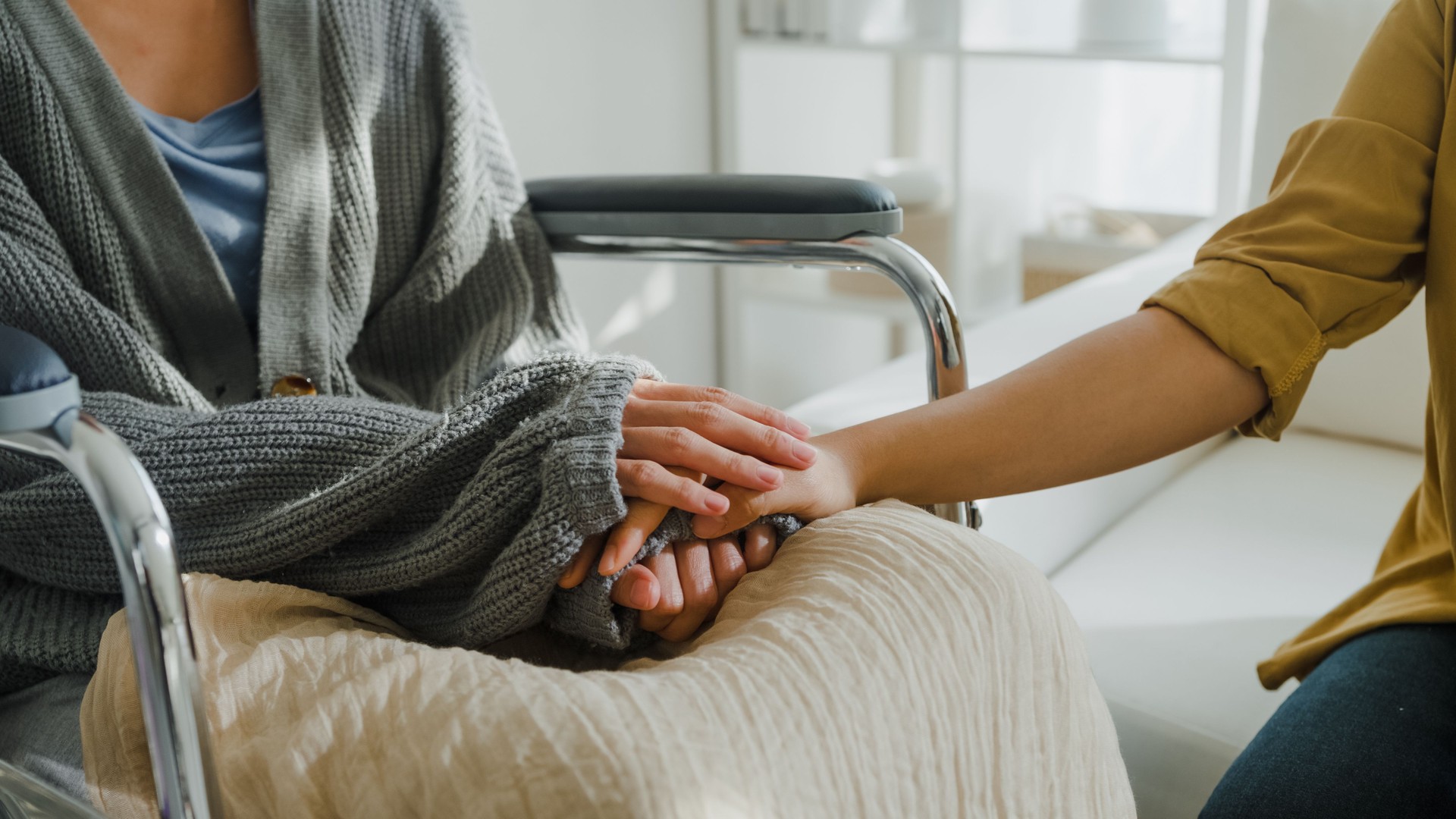 Closeup of young Asian people holding hands trust comfort help cancer patients talk crying stress relief in living room at home. Healthcare.